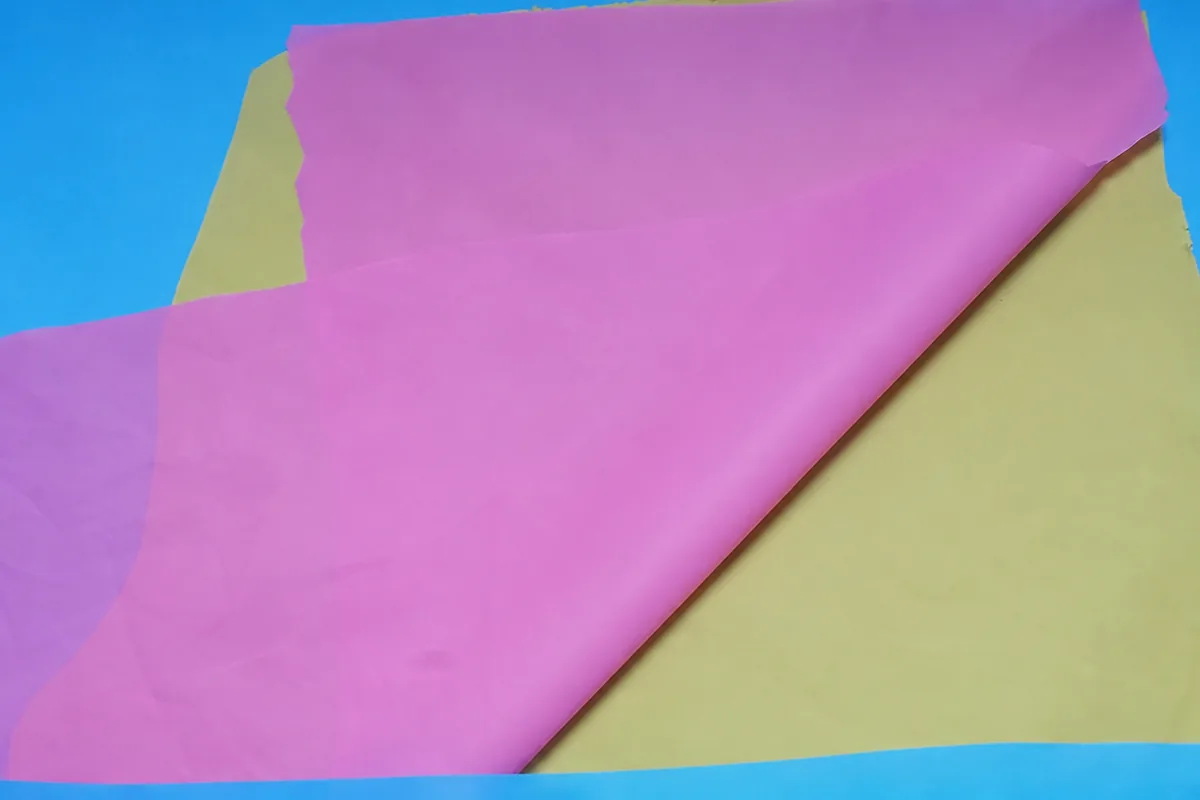 Overlapping pink and pale-yellow flexible film specimens for EVA or PEVA material review