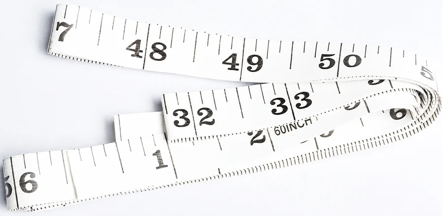 Complete flexible sewing tape extended beside its compact storage case