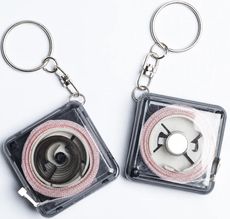 Transparent keychain tape measure cases showing the internal reel, return spring and metal key rings