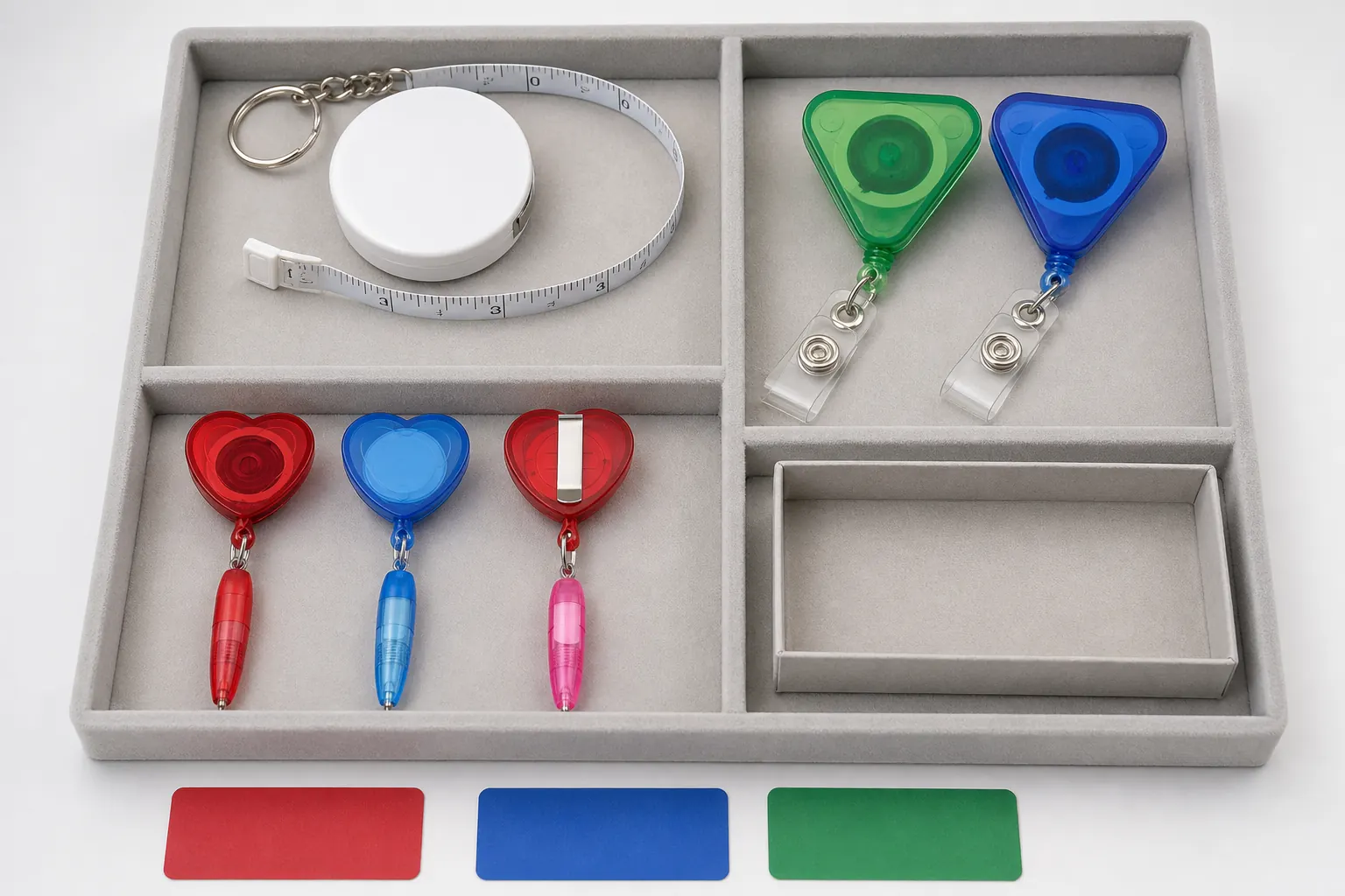 Complete unbranded mini tape measure, retractable badge holders and pen reels separated in an office and event gift approval tray