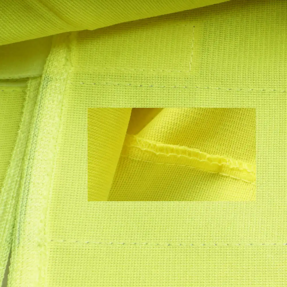 High-visibility vest seam assembly with folded allowance edge binding and overlock detail