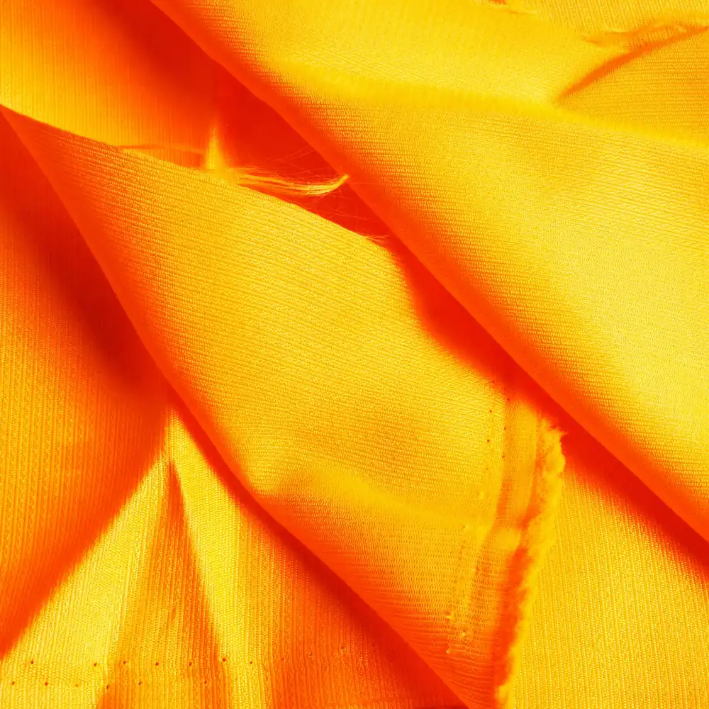 Orange high-visibility woven surface folds cut edge and loose fibers for material review