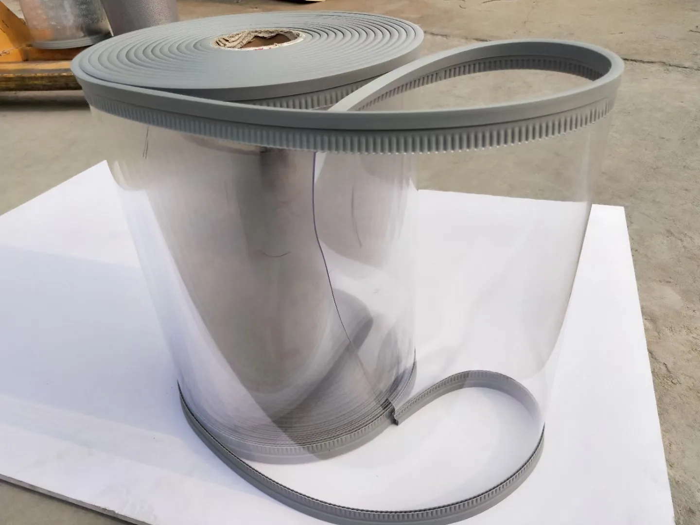 Complete clear flexible panel roll shown with a continuous gray edge carrier on a neutral review sheet.