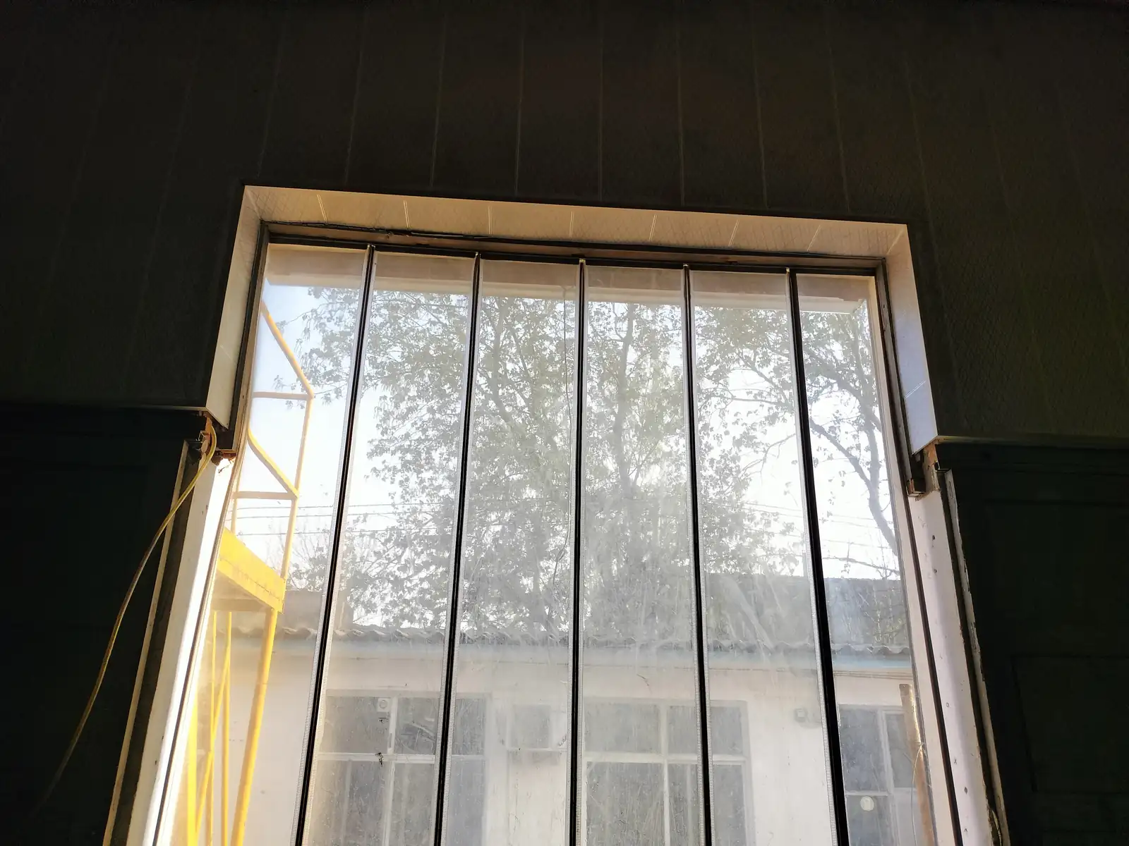 Full transparent magnetic PVC panel doorway viewed from inside an industrial opening.