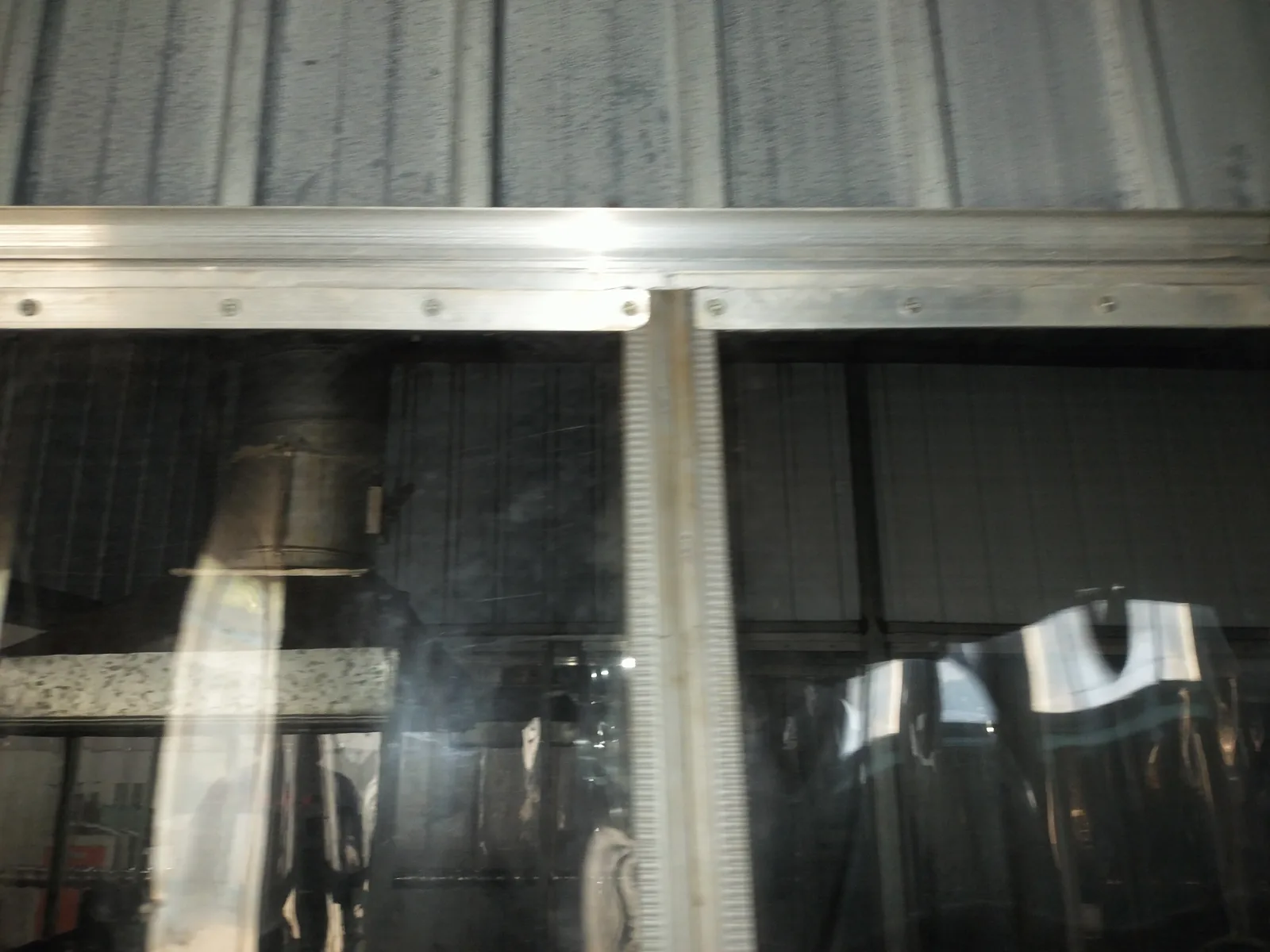 Close view of the upper rail and transparent PVC panels at an industrial opening.