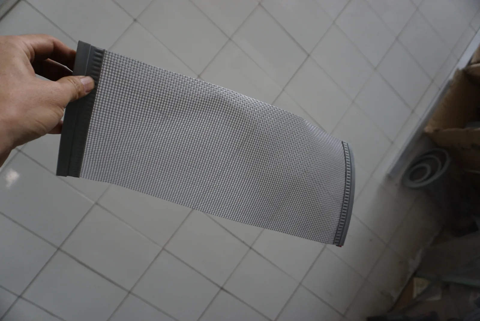 Clear flexible PVC panel with a dark vertical edge carrier held for construction review.